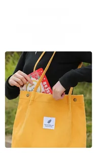 Detail of yellow corduroy tote bag with snap button closure and vertical stripe texture