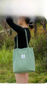 Detail of light green corduroy tote bag with metal buttons on outdoor model