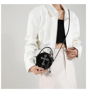 Close-up of black round mini crossbody bag featuring a silver gothic cross and chain