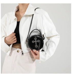 Detail of black glossy leather mini crossbody bag with silver Gothic cross and metal chain