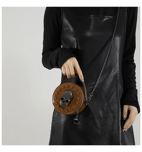 Brown round mini crossbody bag with skull detail and chain strap shown on model