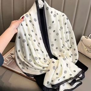 Detail of a white satin scarf featuring black camellia patterns and bold contrast edges