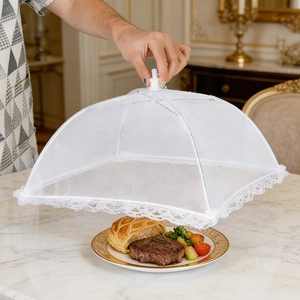 Detail view of foldable white mesh food cover with elegant lace trim over a steak dinner