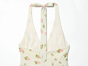 Detail of light green floral halter dress featuring V-neck and a back neck tie bow