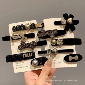 Vue détaillée de pinces à cheveux en velours noir avec perles, cristaux et métal doré