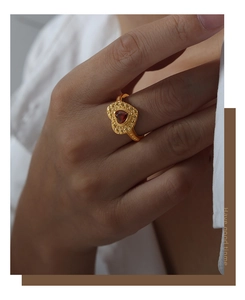 Vue détaillée d'une bague coeur vintage dorée avec une incrustation de zircon rouge