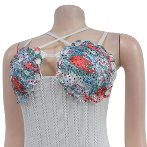 Detail of floral bustier with red rhinestones, shell edge design and crisscross straps