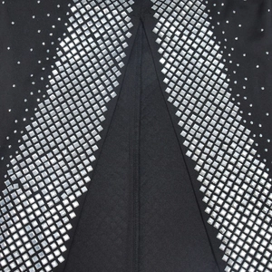 Detail of silver square rhinestones in V-shape pattern on black fabric of the dress