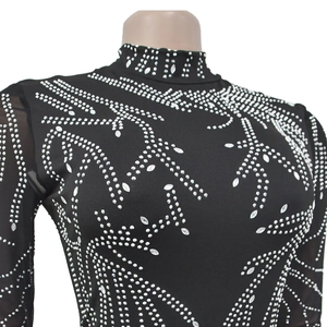 Detail of black turtleneck jumpsuit featuring shimmering silver rhinestones in a sunburst pattern