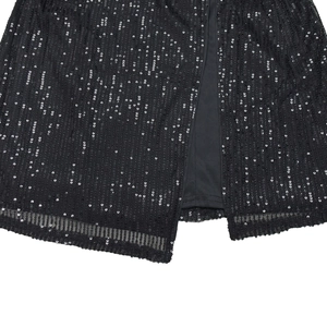 Detail view of black sequin dress featuring sheer mesh fabric and slit design