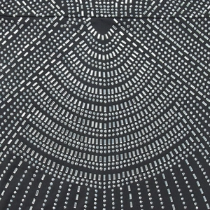 Detailed view of black fabric dress featuring intricate silver rhinestone geometric patterns