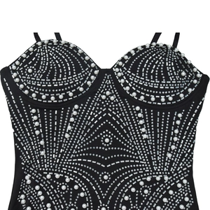 Dettaglio dell'abito a corsetto nero con perle bianche e motivi geometrici di strass