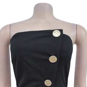 Gros plan d'une combinaison noire sans manches avec boutons dorés et coupe asymétrique