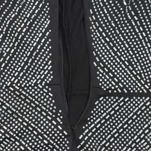 Detailed macro view of rhinestone patterns and invisible zipper on black dress fabric