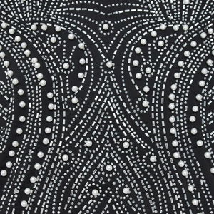 Dettaglio delle intricate decorazioni con strass e perle su tessuto nero profondo