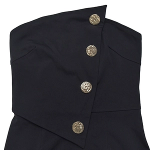 Détail d'une combinaison bustier noire avec boutons dorés en relief sur la patte
