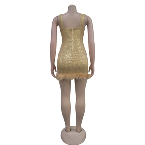 Detailed back view of golden sequin dress featuring feather hem and invisible zipper