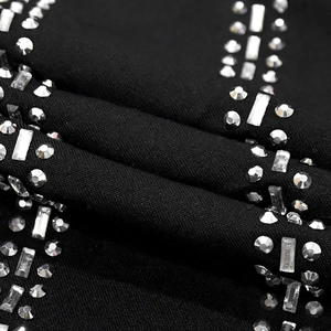 Detailed macro view of sparkling silver rhinestones on black knitted fabric dress