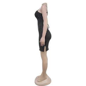 Détail d'une mini robe noire moulante avec motifs en strass et fente latérale