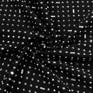 Close-up of black fabric featuring intricate silver rhinestones in varied shapes