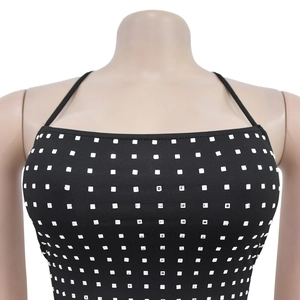 Détail d'une robe courte noire à fines bretelles ornée de strass brillants en carrés