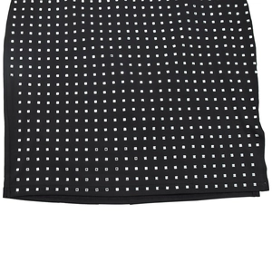 Détail de l'ourlet d'une robe noire avec des strass carrés argentés en motif de grille