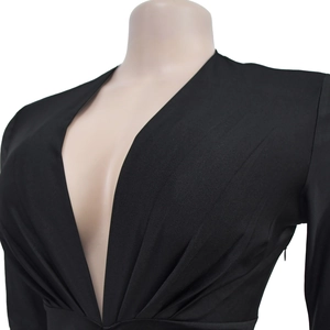 Detail of deep V-neckline and radial pleated texture on a black slim-fit dress