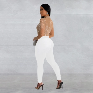 Detail of sheer mesh long sleeve top with crystals and white high waist skinny trousers