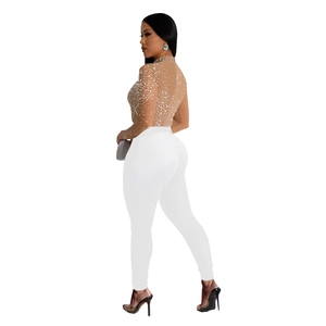 Detail of sheer nude mesh top with sparkling silver rhinestones and white slim pants