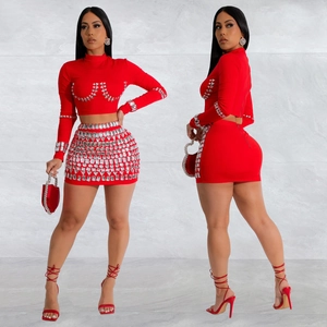 Women's two-piece red knit set with long sleeve crop top and rhinestone mini skirt