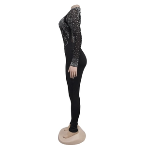 Detail of slim fit black jumpsuit featuring sheer mesh panels and sparkling rhinestones