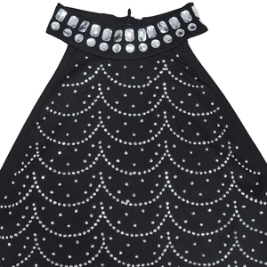 Dettaglio di abito nero con scollo all'americana, grandi strass e motivo a onde