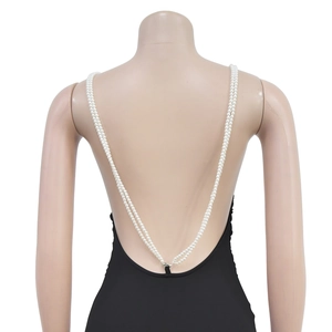 Detail of double-layer pearl body chain attached to a black backless dress