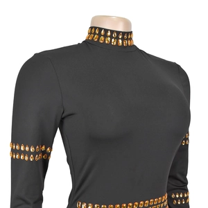 Détail de la robe noire à manches longues avec strass orange sur le col haut et les poignets