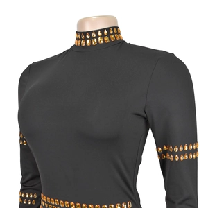 Détail des gemmes gouttelettes or-orange sur le col et les manches de la robe noire chic