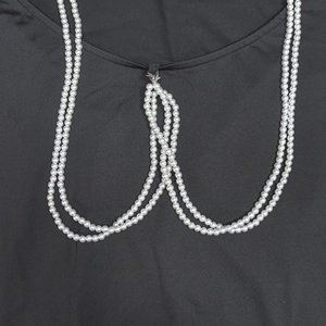 Macro view of a multi-layer white pearl body chain accessory on a black background