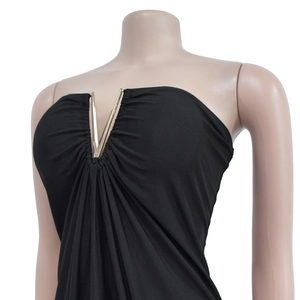Detail of black V-neck dress featuring a gold metal hardware and elegant pleated texture