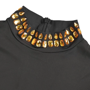 Détail d'une robe noire à col montant avec strass ambrés et fermeture éclair au dos