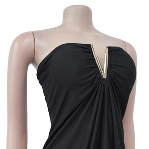 Detail of black V-neck dress featuring a golden metal buckle and gathered pleats