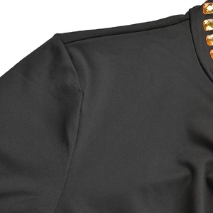 Gros plan du décolleté de robe en tricot noir avec des strass ambrés et détails