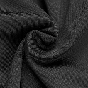 Gros plan sur un tissu en maille noire montrant une texture fine et des plis en spirale