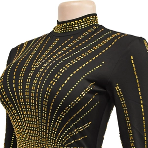 Detail of high neck black dress featuring golden geometric rhinestones and long sleeves