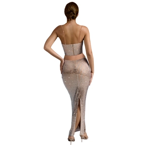 Rear view of silver sequin two-piece set featuring backless crop top and long slit skirt