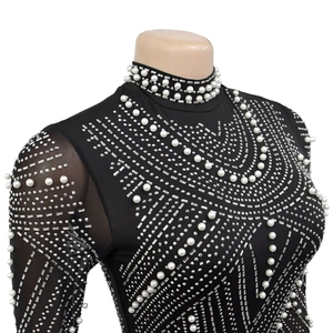 Detail of black rhinestone and white pearl embellishments on sheer mesh long sleeve dress