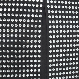 Détail du tissu noir de la robe avec des strass argentés brillants et des coutures fines