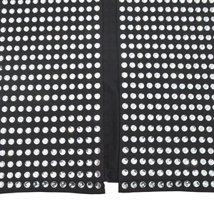 Détail des strass argentés sur tissu noir avec fente latérale de la robe moulante