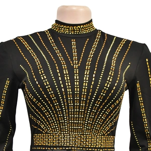 Detail of elegant black long sleeve dress with golden geometric rhinestone patterns