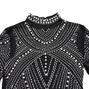 Detail of black high neck dress featuring geometric rhinestones and pearls with mesh sleeves