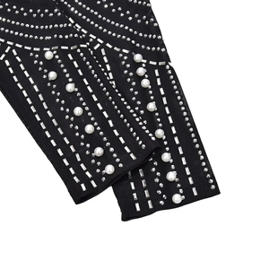 Detail of black slim dress featuring rhinestone geometric lines and white faux pearls