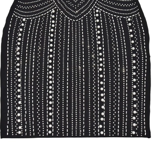 Close-up of intricate white pearls and rhinestones on black bodycon dress fabric